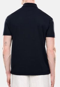 Polo navy con cuello clásico y mangas cortas. Tejido suave, diseño ajustado y detalles de costura sutiles en el dobladillo.
