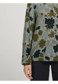 Vihreä kukkakuosisweater, jossa on tekstuurinen pinta, pitkät hihat ja rento istuvuus. Tausta on harmaa, jossa on tummempia ja vaaleampia lehtiä.
