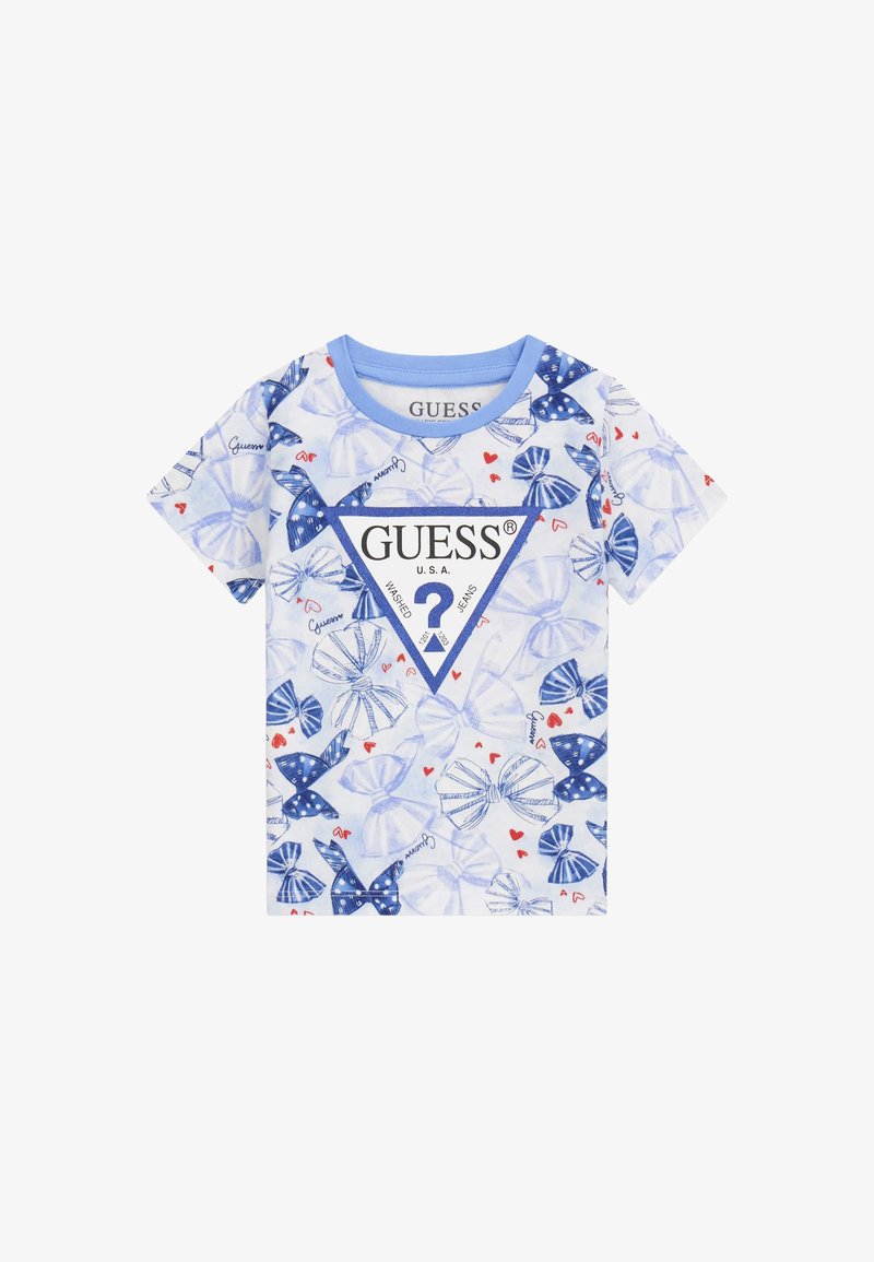 Īsām piedurknēm, zilas un baltas kokvilnas T-krekls ar trīsstūra formālu grafiku, kurā redzams uzraksts "GUESS", loki, sarkani sirdis un punktu raksts.