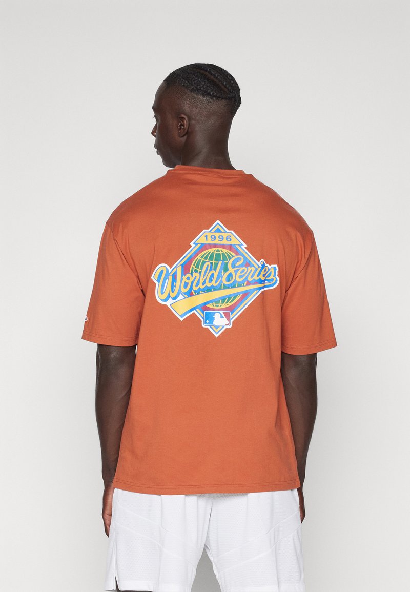 Bruine katoenen t-shirt met een kleurrafiek van de World Series van 1996 op de achterkant. Korte mouwen en een ontspannen pasvorm. Glad textuur.