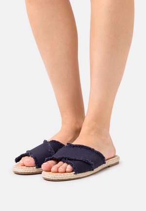 Sandali espadrillas blu navy con fasce in tessuto sfrangiato incrociate sulle dita e suole in juta intrecciata, che mostrano un design casual e strutturato.