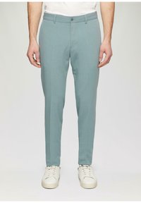 Light blue tailored trousers made of a smooth fabric, featuring a button closure and side pockets, paired with white sneakers.