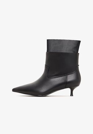 Czarne botki za kostkę z wąskim noskiem, eleganckim skórzanym cholewką i siateczkowym mankietem; mają mały obcas w kształcie kociego pazura oraz subtelne detale wzdłuż szwów.