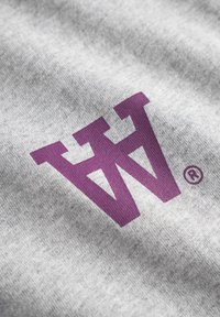 Grå stof med et fremtrædende lilla stiliseret "W" logo med et registreret varemærke symbol. Teksturen synes blød og glat.