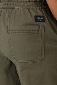 Olive green shorts with an elastic waistband, featuring a rear patch pocket and a small black label with white text sewn on.