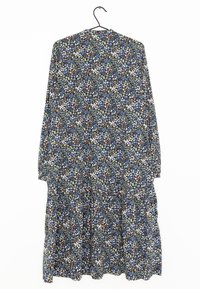 Abito floreale nero con maniche lunghe, caratterizzato da fiori blu, bianchi e arancioni, orlo a strati e scollatura rotonda. Tessuto leggero.