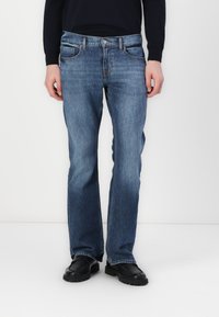 Men's blue denim jeans with a straight leg design, five pockets, and a button and zipper closure. Smooth texture with slight fading.