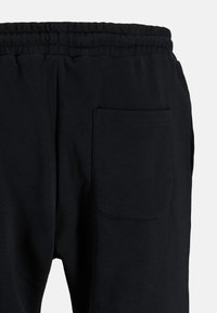 Sorte bomulds-sweatpants med elastisk talje, med en enkelt lomme på bagsiden og et blødt, struktureret stof.