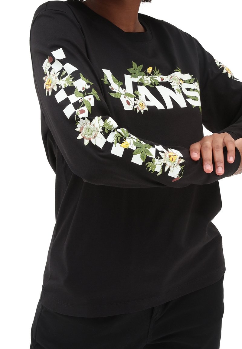 Chemise noire à manches longues avec texte blanc "VANS", accents floraux et motif à damier sur les manches. Fabriquée en coton doux et léger.