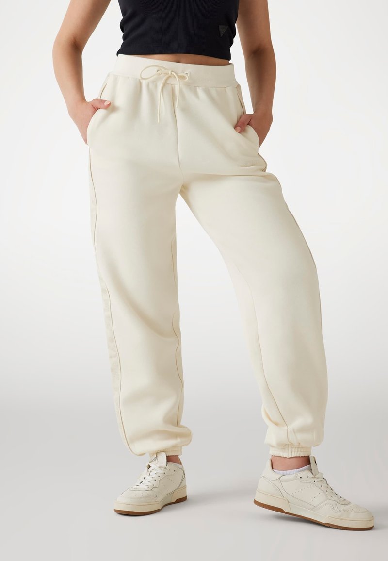 Crème-kleurige sweatpants van zachte stof, met een elastische tailleband met een trekkoord, zijzakken en taps toelopende manchetten.