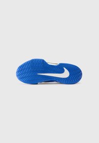 Blå og hvit sportsko såle med et teksturert mønster, som har en fremtredende hvit Nike-logo og et flatt, vinklet design.