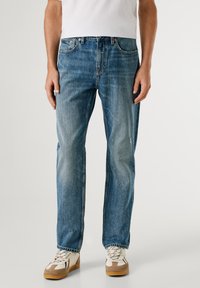 Heledad hallid teksad sirge säärega, nähtava õmblusega ja kerge tuhmumisega. Omab eesmine taskuid ja nööbiga sulgemist.