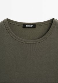 T-shirt col rond vert olive avec couture visible et une étiquette noire à l'intérieur du col portant l'inscription "Massimo Dutti Made in Portugal".