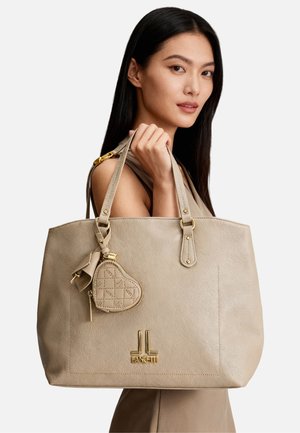 Borsa tote in pelle beige con due manici allungati, arricchita da un piccolo charm a forma di cuore e accessori in metallo color oro. Logo in rilievo sulla parte anteriore.