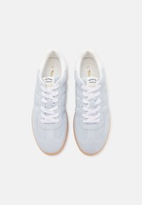 Paire de baskets en daim bleu clair avec lacets blancs et semelles en caoutchouc naturel, vues de dessus sur fond blanc.