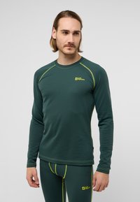 Haut thermique à manches longues en vert foncé avec un tissu texturé, rehaussé de surpiqûres jaunes vives et d'un logo. Design ajusté pour le superposition.