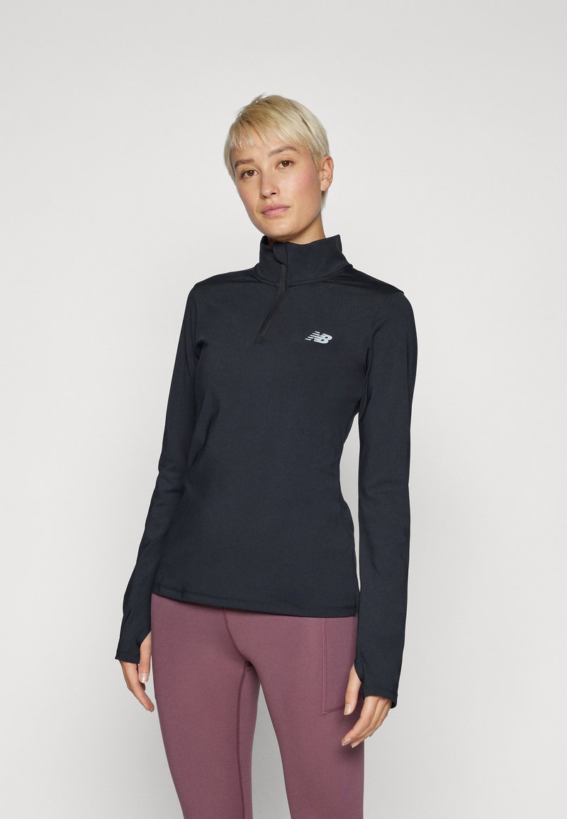 Maglietta sportiva nera a maniche lunghe con collo a mezza zip e design aderente. Presenta un piccolo logo riflettente sul petto. Tessuto morbido e liscio.