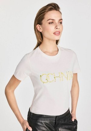 Biała bawełniana koszulka z krótkim rękawem z napisem "OCHNIK" w żółtej, kwiatowej czcionce. Gładka tekstura, klasyczny dekolt typu crew neck.