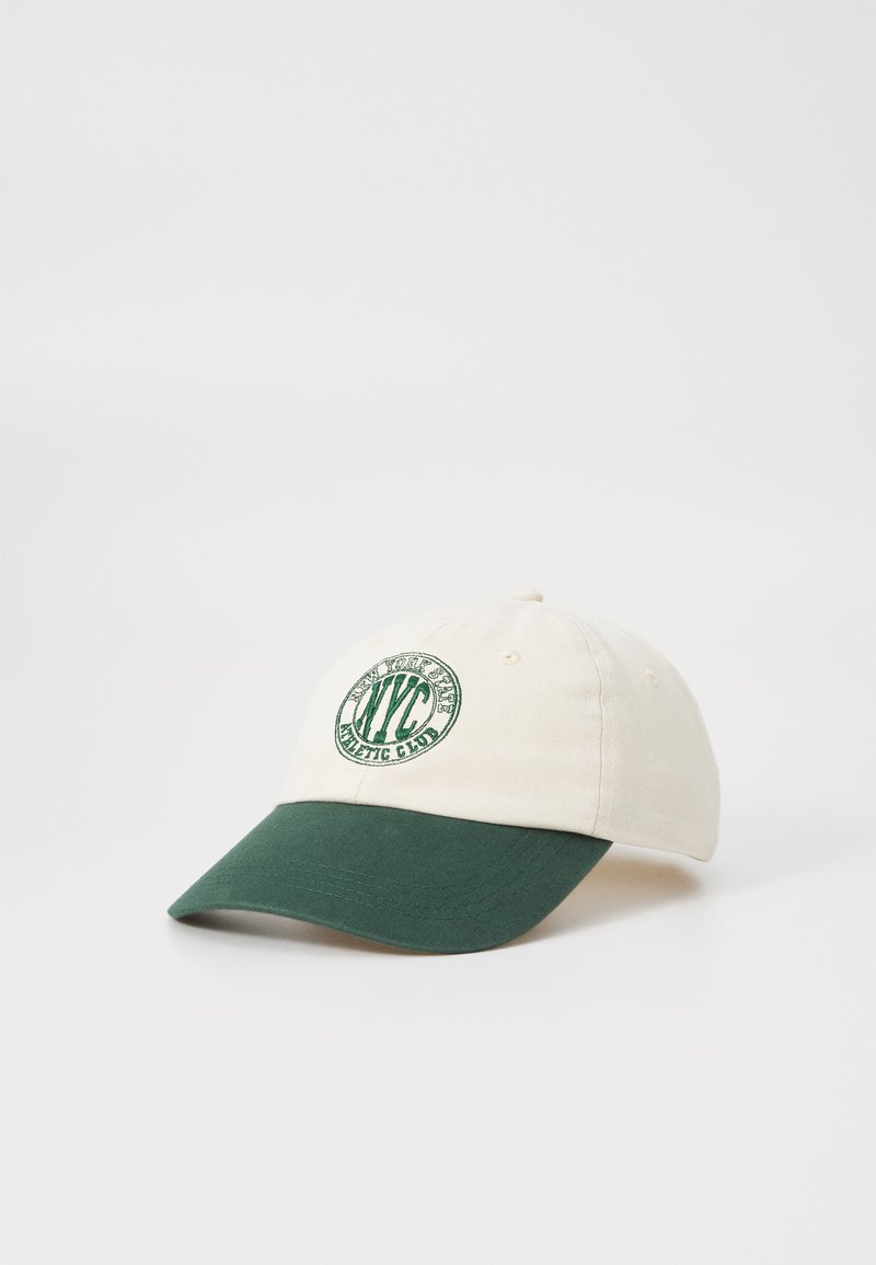 Baseball-Mütze mit einer cremigen Krone und einem dunkelgrünen Schirm. Enthält ein gesticktes, kreisförmiges Logo in grün. Aus Baumwollmaterial, strukturierte Form.