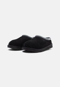 Chaussons en suède noir avec une surface texturée, ornés d'une bordure contrastante à motif cousue et d'une semelle en caoutchouc pour l'adhérence.