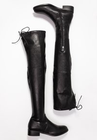 Schwarze Kunstleder-Stiefel mit Schlangenlederoptik über dem Knie, mit niedrigen Blockabsätzen und Schnürungen hinten. Ein Stiefel im seitlichen Blick, der andere mit sichtbarem Innenreißverschluss.