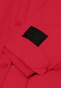 Rode gewatteerde jas met een gestructureerd oppervlak, een zwart label met "FABIENNE CHAPOT" en een knoopsluiting aan de voorkant.