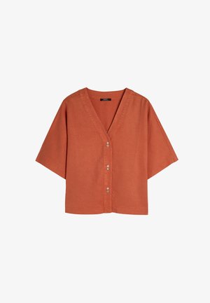 Rdzawoczerwona, krótko rękawowa koszula z dekoltem w serek i z przodem na guziki. Wykonana z teksturowanej tkaniny, ma luźny krój i prosty dół.