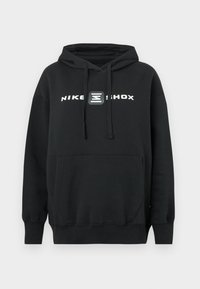 Fekete Nike Shox kapucnis pulóver elülső kenguruzsebbel és húzózsinóros kapucnival, a mellkason fehér logóval és grafikával.