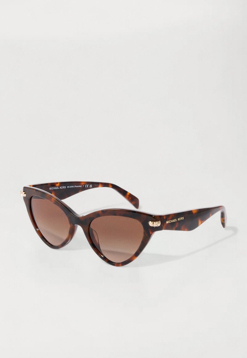 Occhiali da sole a forma di gatto con motivo tartarugato e lenti marroni graduali. Presentano dettagli in tono oro sulle astine, con il marchio "Michael Kors."