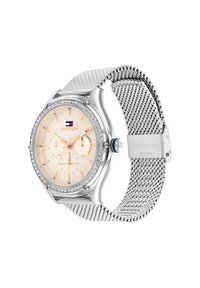 Reloj en tono plata con correa de malla, esfera texturizada en color beige, bisel brillante y acentos azules en las manecillas; cuenta con indicadores de fecha y día.