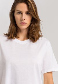 Bílý bavlněný tričko s krátkými rukávy, kulatým výstřihem a měkkou texturou, které má jednoduchý a klasický design.