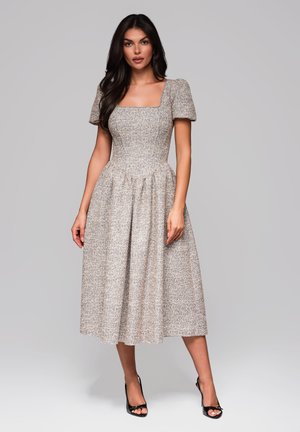 Blommönstrad midiklänning med fyrkantig halsringning, puffärmar och en figurnära bodice som övergår till en fladdrande kjol. Färgerna inkluderar beige och pastell.