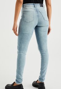 Ljust blåa skinny jeans i denim med hög midja, två bakfickor och en urtvättad design. Matchat med svarta loafers.