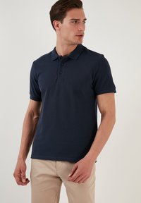Polo de manga corta en color navy, confeccionado en suave tela de algodón, con una tapeta de tres botones, cuello tipo polo y un diseño ajustado.