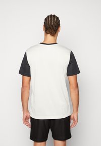 Camiseta deportiva de manga corta con cuerpo en gris claro y mangas en negro, fabricada con tejido que absorbe la humedad, con un diseño de cuello redondo.