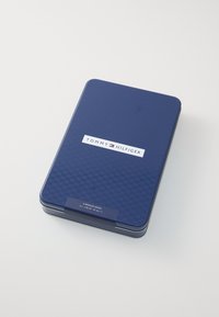Dunkelblaue Metallbox mit strukturiertem Oberflächenfinish, versehen mit einem weißen Logo und einem Etikett, das den Inhalt anzeigt: sechs normale Socken in verschiedenen Größen.