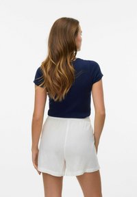 Jūras spēku zilo ribotu īsām piedurknēm topu, kas apvienots ar baltām linu šortiem, demonstrējot pieguļošu dizainu un mīkstu tekstūru, skatoties no aizmugures.