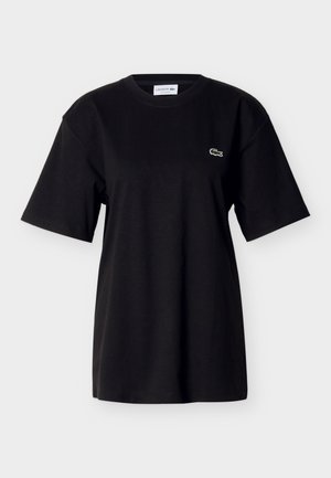 T-shirt en coton noir à manches courtes, coupe décontractée, col rond, avec un petit logo crocodile vert brodé sur le devant.