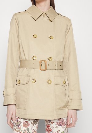 Beige dubbelknäppt trenchcoat med guldknappar, belagd midja, stora fickor och axelklaffar. Slät tygstruktur.