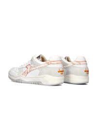 Sneakers bianchi in suede e pelle texturizzati, con dettagli arancioni e un design retrò. Profilo a basso taglio con colletto imbottito.