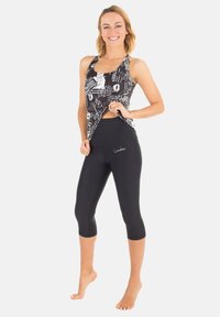 Svart och vit mönstrad linne med racerback-design, parat med svarta capri leggings med en åtsittande silhuett.