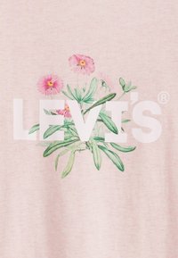 Helles rosa Baumwollgewebe mit floralem Design, das rosa Blumen und grüne Blätter zeigt, overlay mit dem kräftigen weißen Text "LEVI'S".