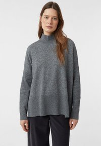 Grau gestrickter Rollkragenpullover aus weichem Material, mit lässiger Passform, geripptem Saum und langen Ärmeln mit strukturierten Bündchen.