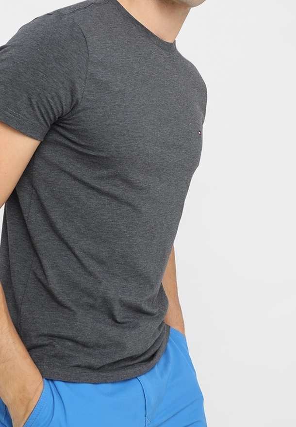 T-shirt grigio a maniche corte realizzato in tessuto morbido, con scollatura a girocollo e piccolo logo sul petto, indossato con pantaloni corti blu.