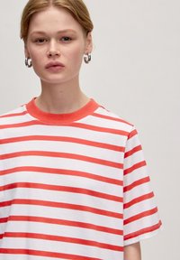 Gestreiftes T-Shirt mit rot-weißen horizontalen Streifen, ausgestattet mit Rundhalsausschnitt und kurzen Ärmeln, aus leichtem Baumwollstoff gefertigt.