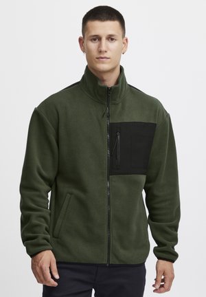 Grüne Fleecejacke mit hohem Kragen, schwarzem Reißverschlusstaschen auf der Brust, Seitentaschen und kontrastierenden schwarzen Schulterakzenten.