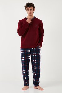 Červený fleecový top s dlhým rukávom a okrúhlym výstrihom, spolu s námorníckymi károvanými nohavicami z flanelu, ktoré majú biele a červené kockované vzory.