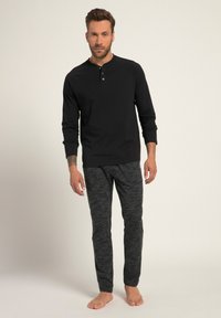 Musta pitkähihainen henley-paita nappien kera, yhdistettynä tummanharmaisiin, teksturoituihin yöpukuhousuihin. Slim fit, minimalistinen muotoilu, ei kuvioita, paljain jaloin.