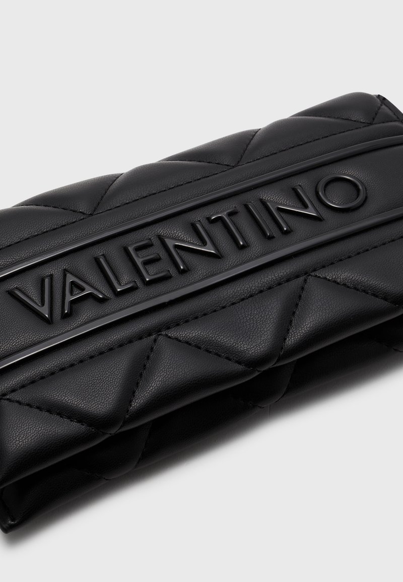 Pochette en cuir noir avec un design matelassé, un logo en relief bien en vue et une finition texturée pour un intérêt visuel supplémentaire.