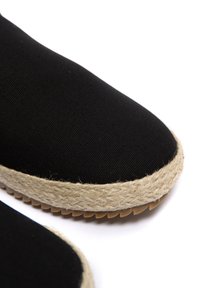 Czarna kanwa espadrille z plecioną podeszwą z juty. Posiada okrągły czubek oraz fakturowaną powierzchnię. Wzmocnione szwy wzdłuż krawędzi.